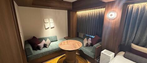 A modern room with a sofa, a round wooden table, and a built-in heater.
