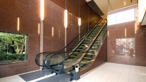 Een binnentrapband in een modern gebouw met granieten wanden en glazen leuningen.