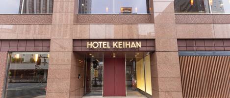 A modern hotel entrance with a prominent sign reading "HOTEL KEIHAN".