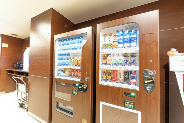 Two vending machines in a room with wooden paneling.
