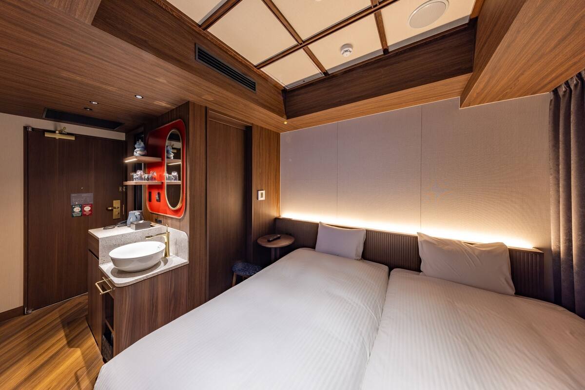 A modern hotel room with a large bed, a built-in vanity with a sink, and a small round table.