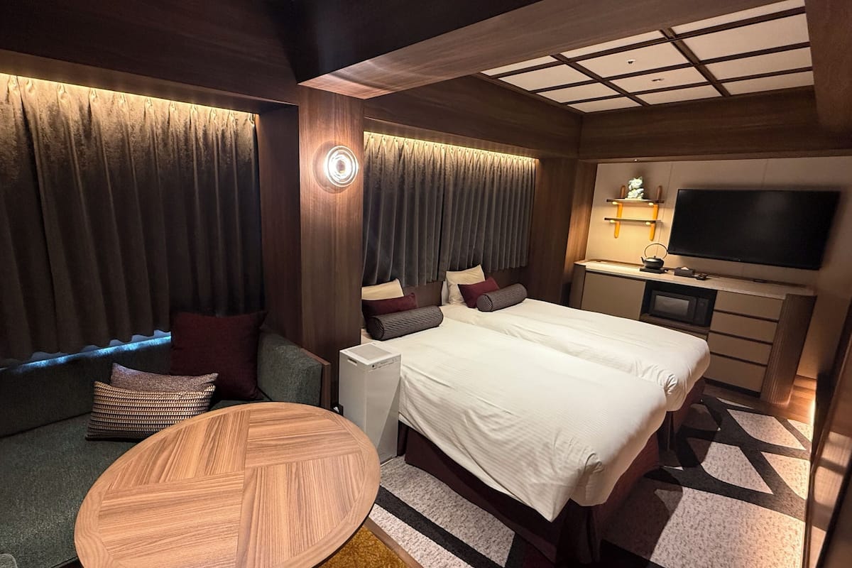 A hotel room with a bed, a TV, a small table, and a sofa.