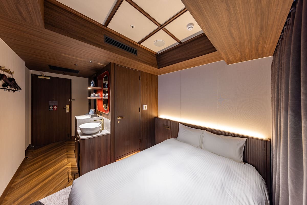 A hotel room with a large bed, wooden ceiling, and a built-in vanity with a mirror and sink.