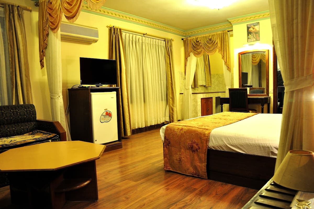 Una habitación de hotel con una cama, un escritorio, un televisor y una silla.