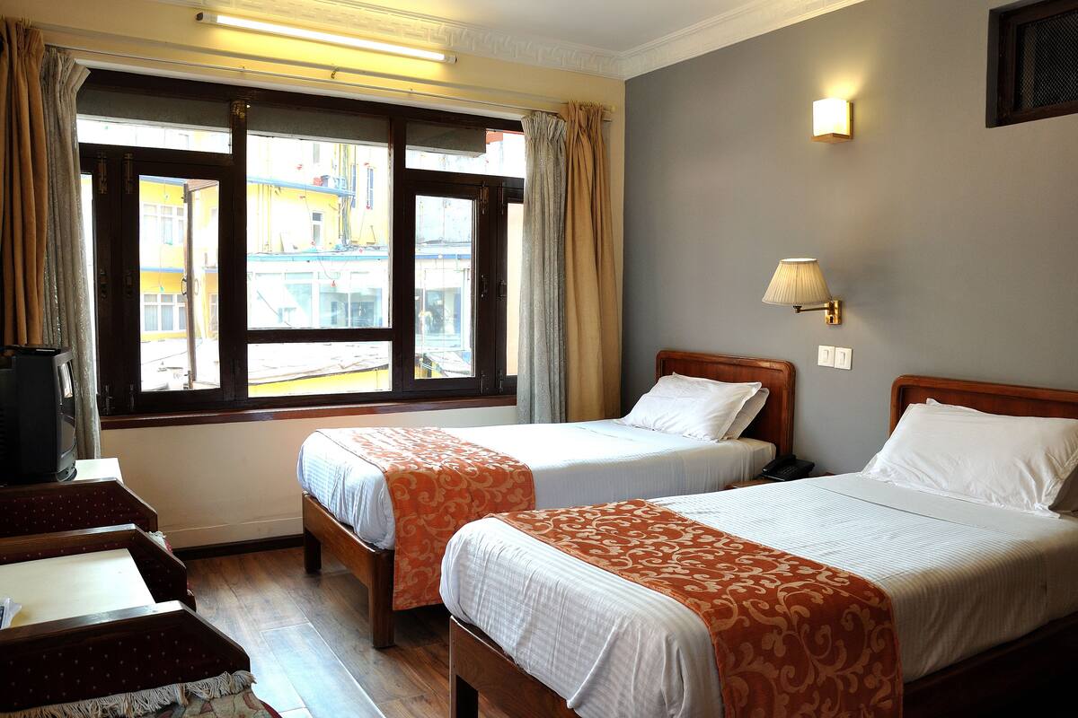 Una habitación de hotel con dos camas, un escritorio y una ventana con cortinas.