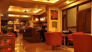 A hotel lobby with a reception desk, red chairs, a ceiling fan, and a bar area. - Tibet Guest House (Kathmandu)