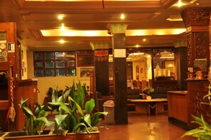 Un interno tradizionale con mobili in legno, un pilastro centrale e un cartello che indica un ristorante.
