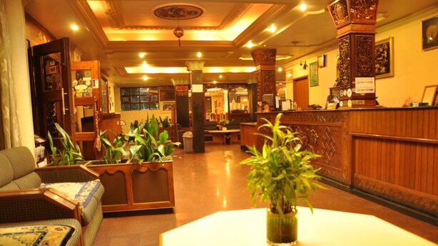 A lobby with a reception desk, seating area, and decorative plants. - Tibet Guest House (Kathmandu)