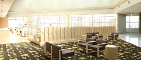 A spacious lobby with a patterned carpet, seating area, and a reception desk.