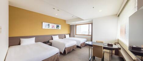 A hotel room with three beds, a desk, and a chair.