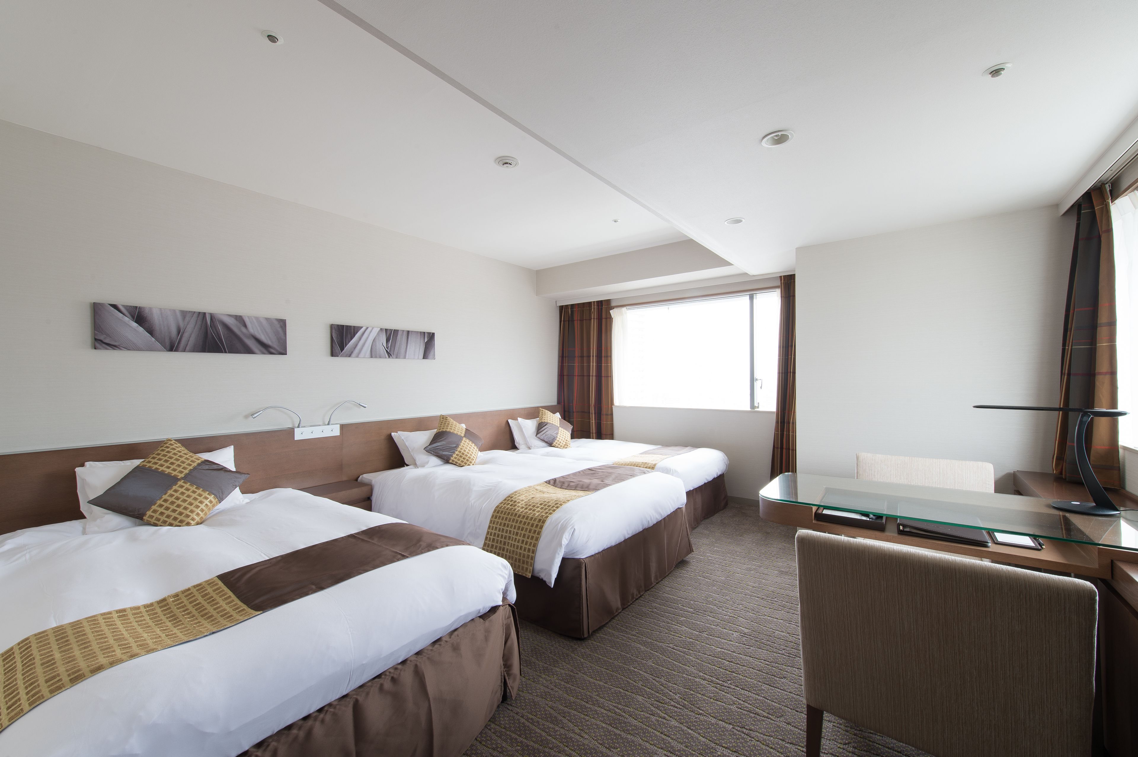 A hotel room with two beds, a desk, and a chair.