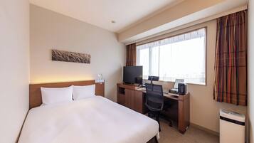 A hotel room with a bed, desk, television, and a window with curtains.