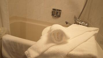 Un baño con una bañera, un perchero con una toalla doblada y un cabezal de ducha.
