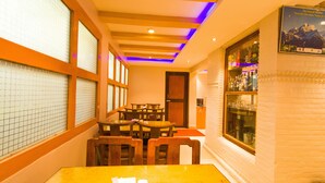 A restaurant with wooden tables and chairs, a large window with a view, and a wall-mounted menu board. - Hotel Blue Horizon (Kathmandu)