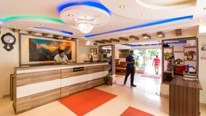 A reception area with a wooden reception desk, a chandelier, and a painting on the wall. - Hotel Blue Horizon (Kathmandu)