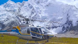 A helicopter parked on a grassy area with a mountainous backdrop. - Hotel Blue Horizon (Kathmandu)