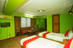 A hotel room with two beds, a sofa, a television, and a desk with a lamp. - Hotel Blue Horizon (Kathmandu)
