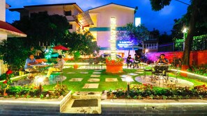 An outdoor dining area with tables and chairs, surrounded by potted plants and a central water feature. - Hotel Blue Horizon (Kathmandu)