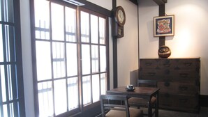A room with a wooden table and chairs, a clock on the wall, and a dresser with drawers. - Kagariya (Kyoto)