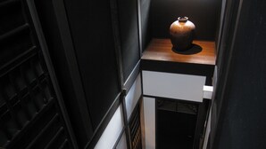 A staircase with a wooden handrail and a small table with a vase on top. - Kagariya (Kyoto)