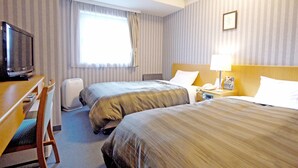 A hotel room with two beds, a desk with a television, a bedside table with a lamp, and a window with curtains. - Hotel Route-Inn Sapporo Shiroishi (Sapporo)