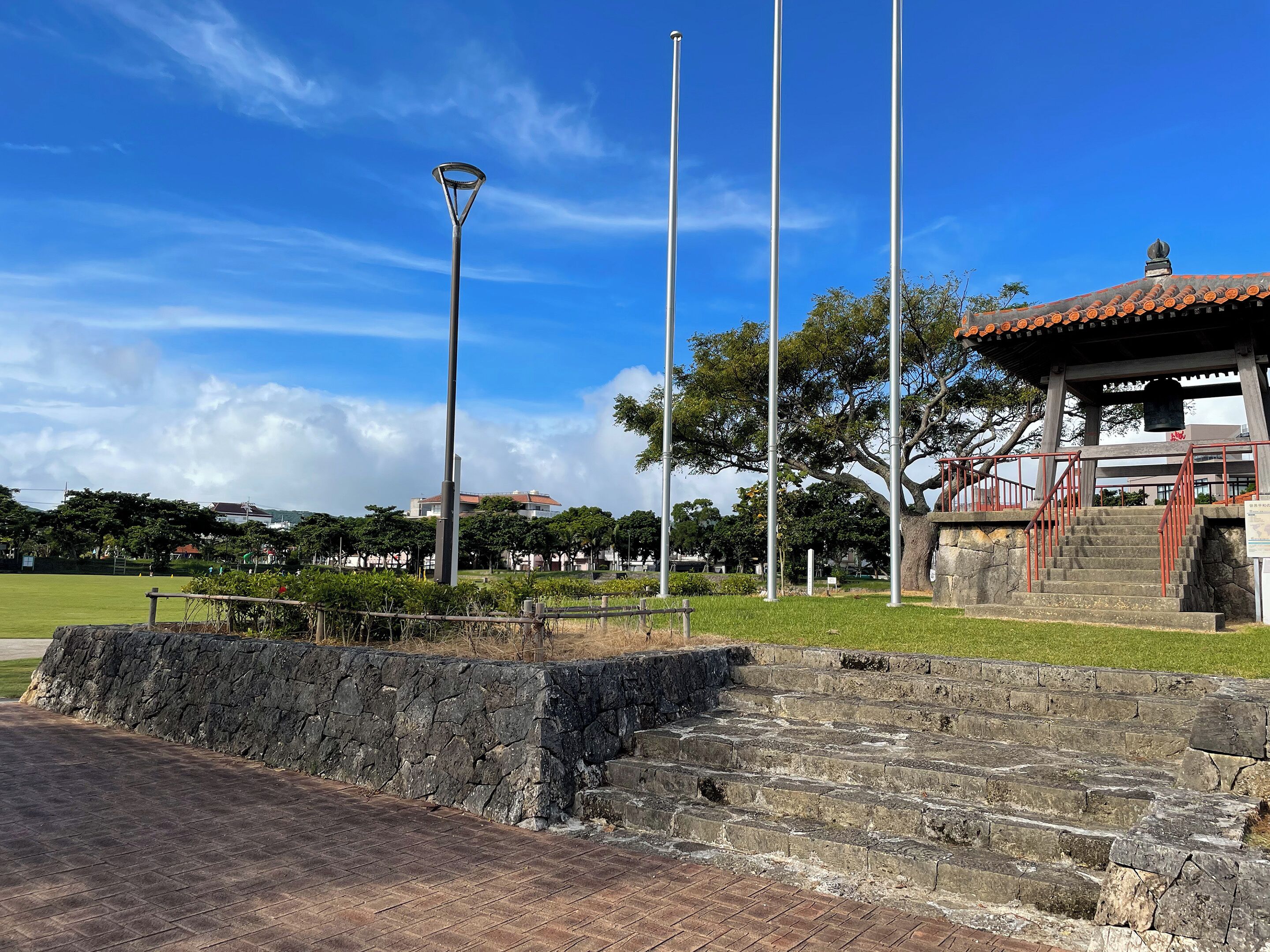 A park with a stone staircase, a metal lamp post, and a traditional pavilion.