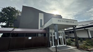 A building with a covered entrance, signage, and a gated area. - Hotel Route-Inn Dai-Ichi Nagano (Nagano)