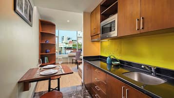 A modern kitchen with wooden cabinets, a black countertop, and a yellow backsplash.