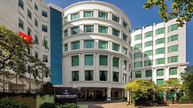 A hotel with a curved facade, multiple windows, and a sign for "The Hanoi Club Hotel & Residences." - The Hanoi Club Hotel & Residences (Hanoi)