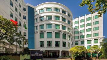 A hotel with a curved facade, multiple windows, and a sign for "The Hanoi Club Hotel & Residences."
