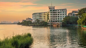 Un hotel a più piani con balconi, affacciato su un fiume con vista sullo skyline della città.