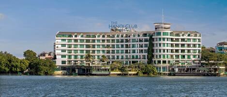 A multi-story hotel with a central tower, located by a body of water.