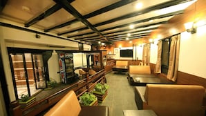 Un restaurant avec des bancs et des tables en bois, un comptoir avec un réfrigérateur à boissons Pepsi et un téléviseur fixé au mur.
