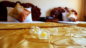 A bed with a golden bedspread and white flowers, wooden headboard, and pillows. - Star Hotel (Battambang)