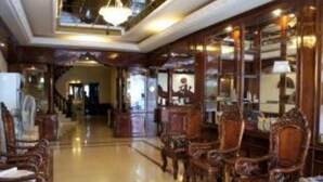 A spacious hallway with ornate wooden furniture, a chandelier, and a polished floor. - Star Hotel (Battambang)