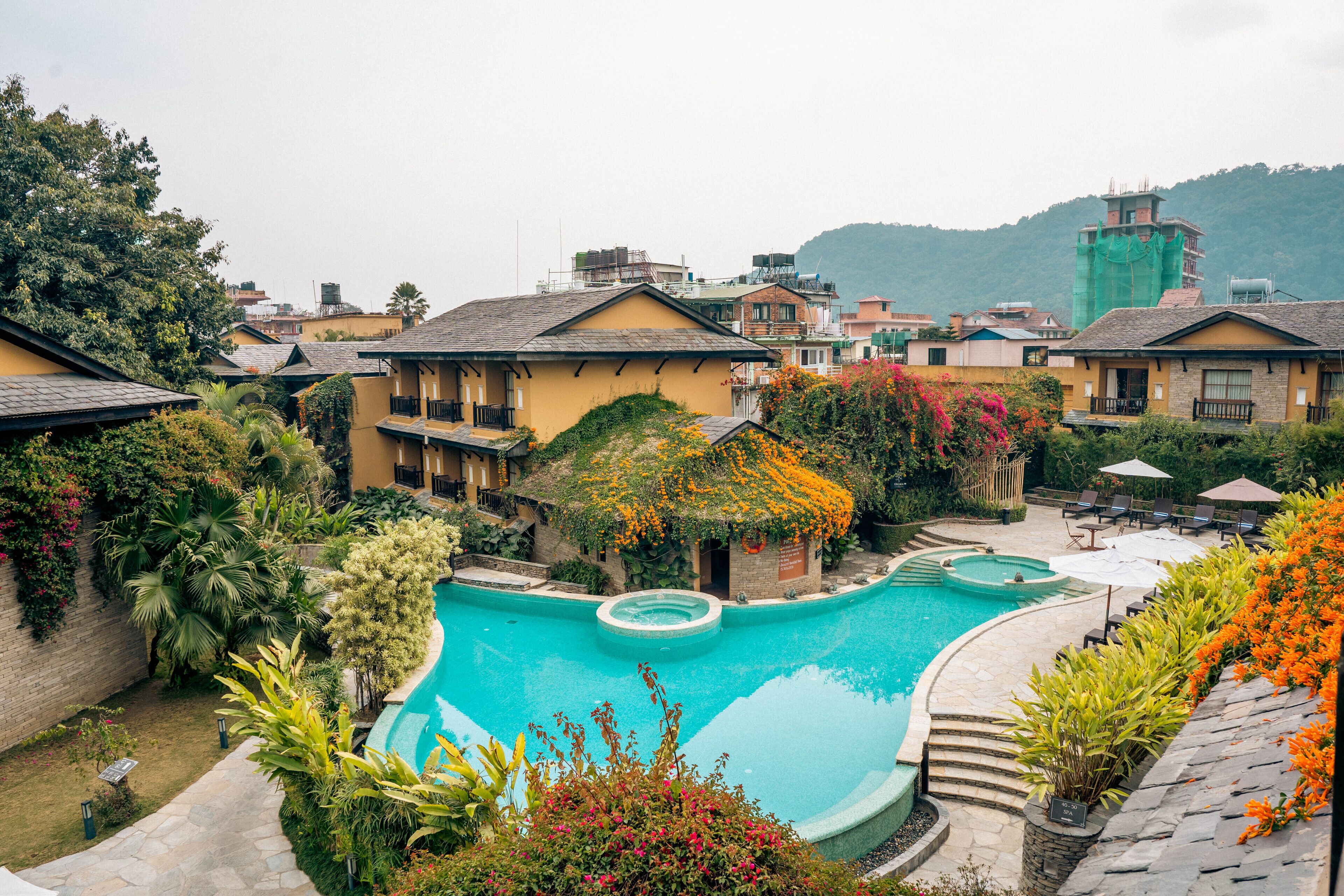 A resort with a swimming pool, multiple buildings, and lush greenery.