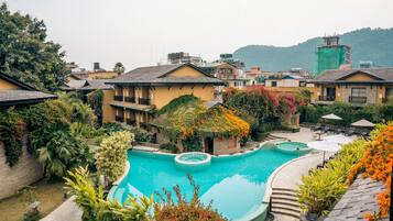 A resort with a swimming pool, multiple buildings, and lush greenery.