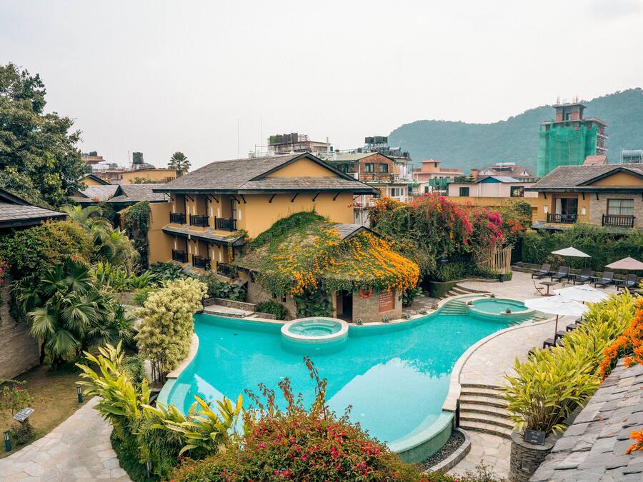 A resort with a swimming pool, multiple buildings, and lush greenery.