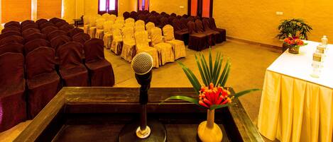 Un salón de conferencias con filas de sillas, un atril y una mesa con un florero.