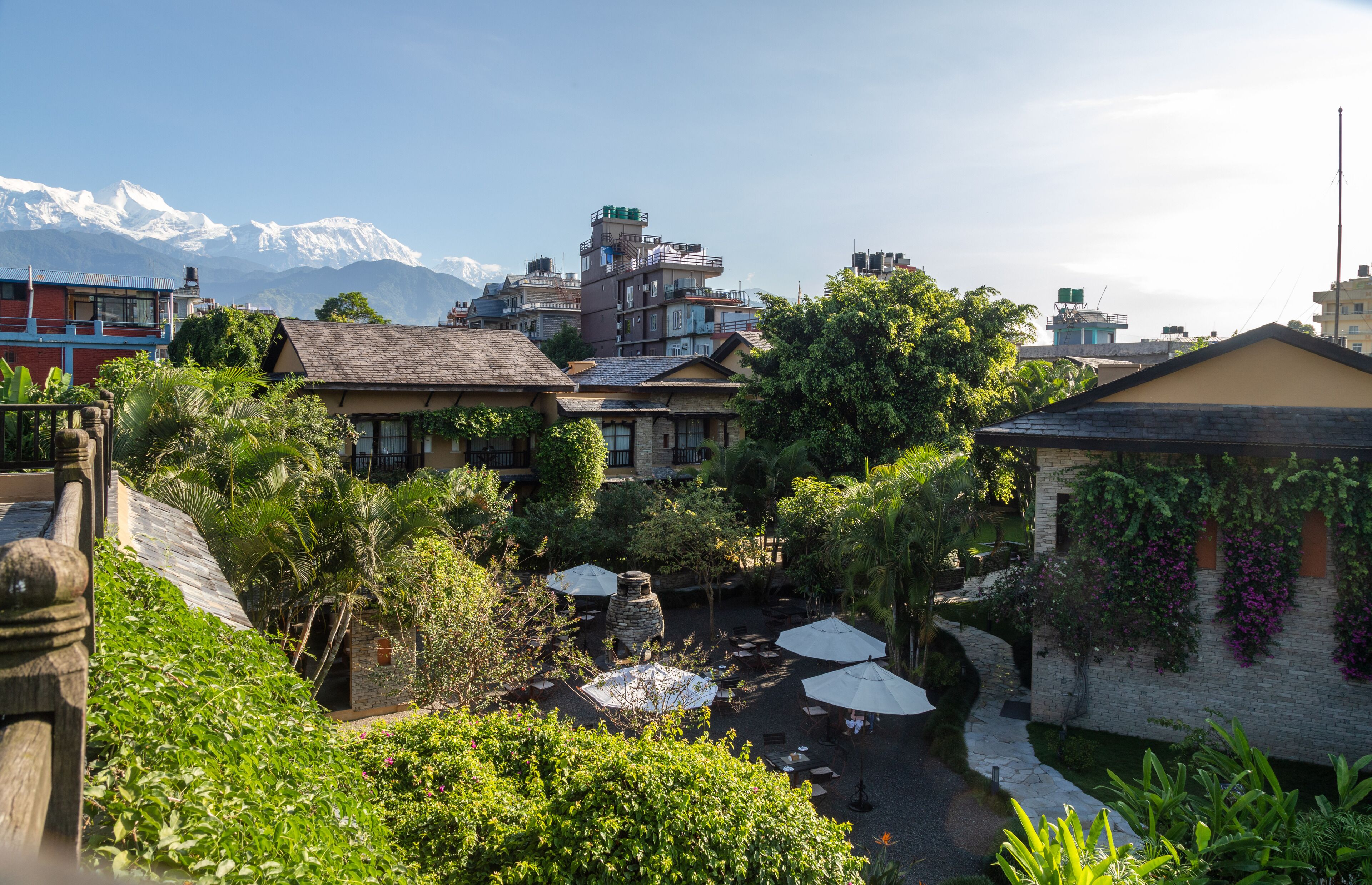 A courtyard with outdoor seating, surrounded by buildings and a mountain range in the background.