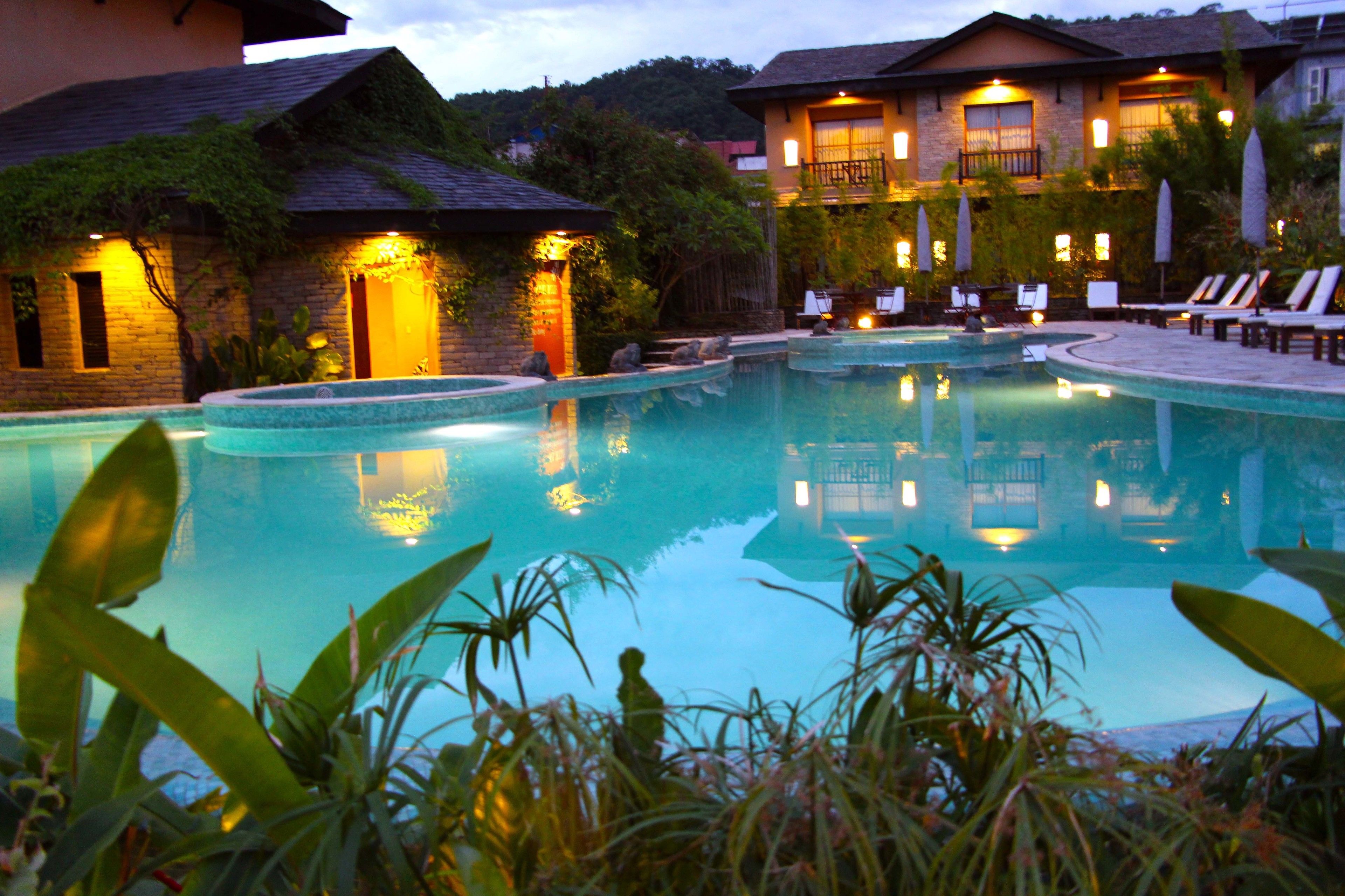 A swimming pool with lounge chairs and a building with a balcony.