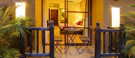 A hotel entrance with a wooden gate, a bench, and a table with chairs outside.