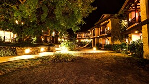 Un patio con hamaca, paredes de piedra y edificios iluminados durante la noche.