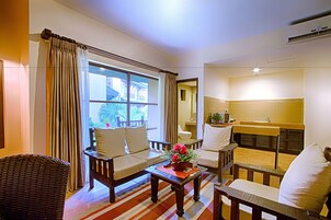 Una sala de estar con sofá, sillones, una mesa de centro con un florero y vistas al exterior a través de una ventana.