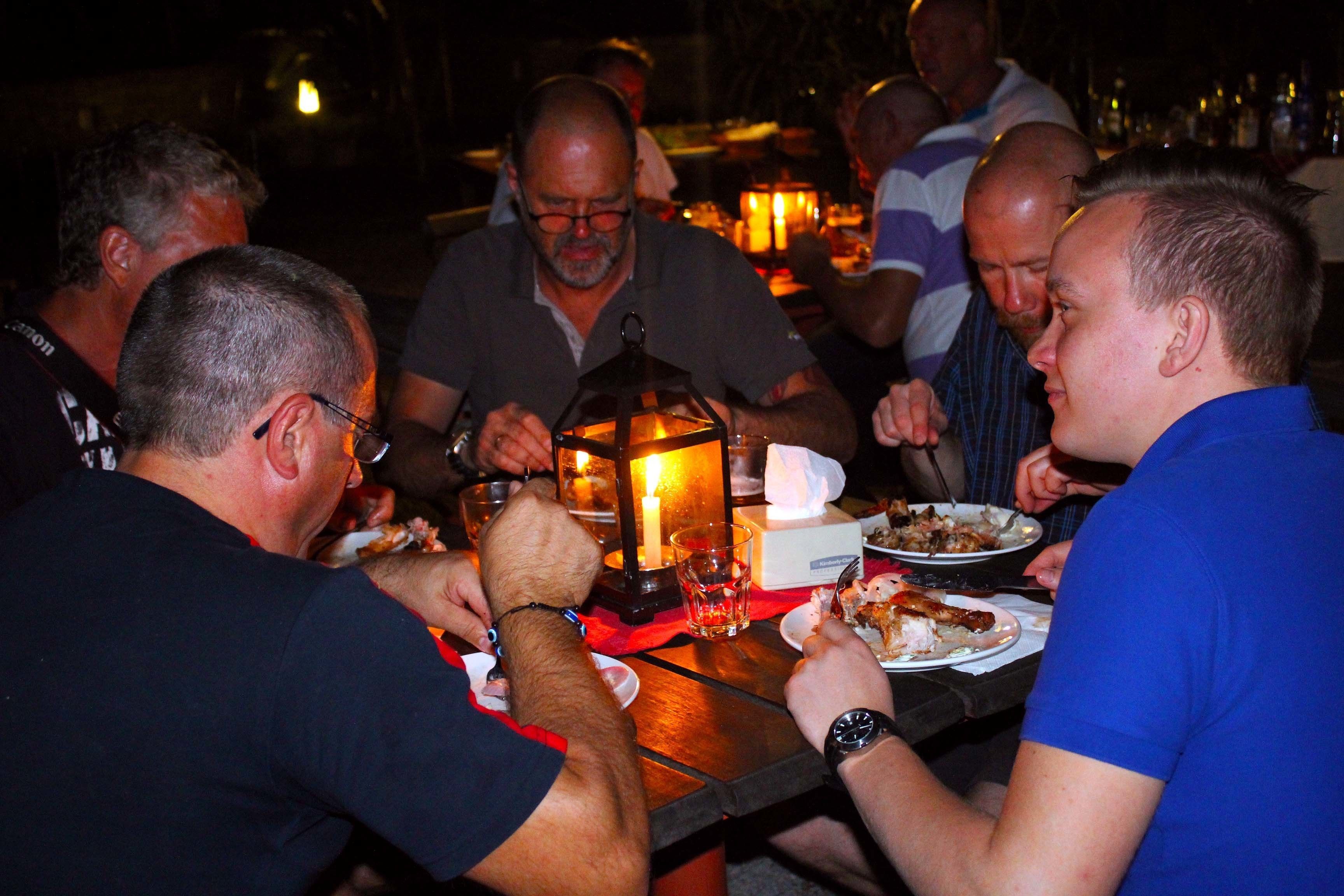 A group of people dining at a table with a candle centerpiece.