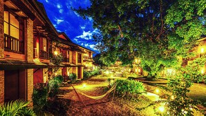 Un patio con una hamaca, senderos bien iluminados y edificios de estilo tradicional.