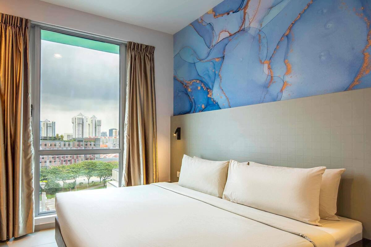 A hotel room with a large bed, a view of the cityscape, and a marble wall.