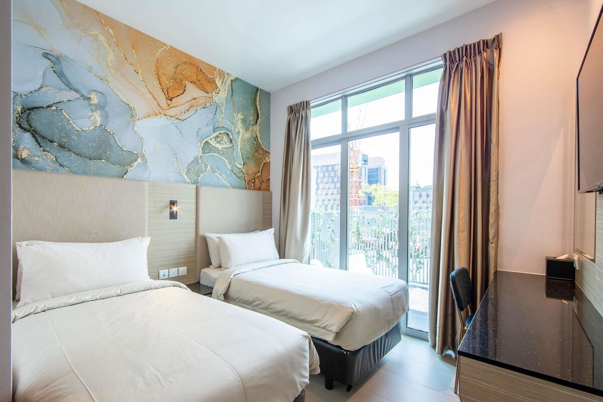Habitación de hotel con dos camas, un ventanal con cortinas, un escritorio y una pared con diseño tipo mármol.