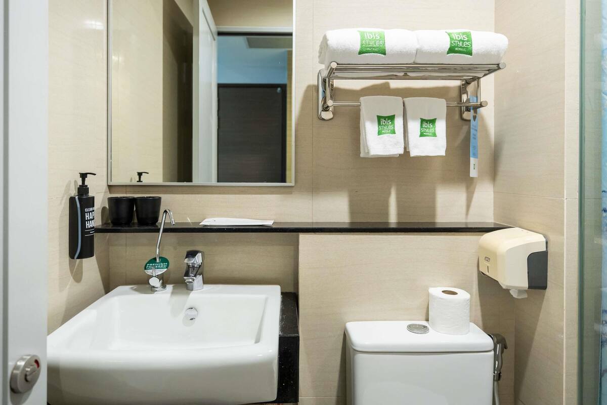 Un baño con lavamanos, inodoro y perchero para toallas.