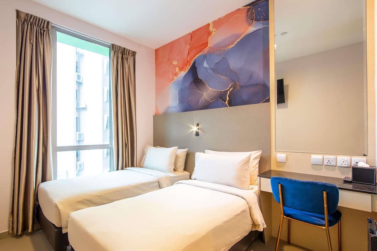 A hotel room with two beds, a desk, a chair, a large mirror, and a wall with abstract art.